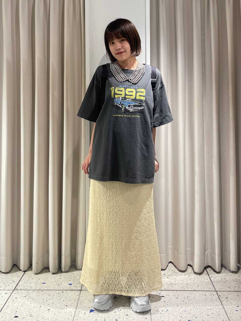 イエロー系のスカート、シルバー系のスニーカー、ブラック系のバックパック/リュックを着用したレディースの夏コーディネートの5枚目の写真