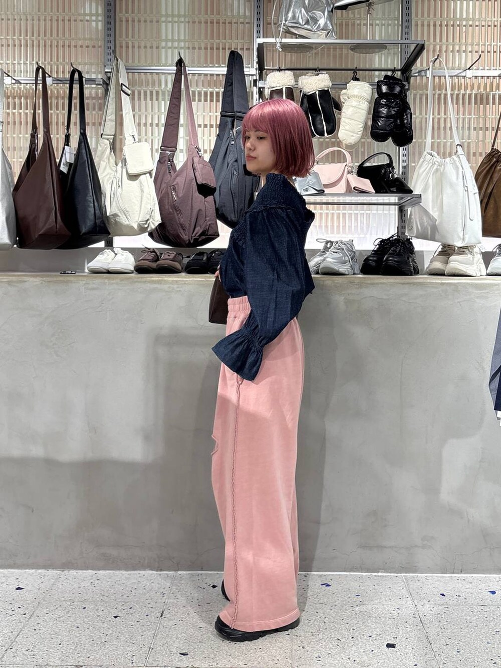 ブラック系のブーツ、ブラウン系のショルダーバッグ、ピンク系のスウェットパンツを着用したレディースの冬コーディネートの2枚目の写真