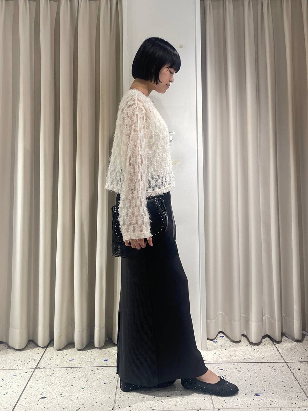 ブラック系のスカート、ブラック系のバレエシューズ、ブラック系のショルダーバッグを着用したレディースの秋コーディネートの2枚目の写真