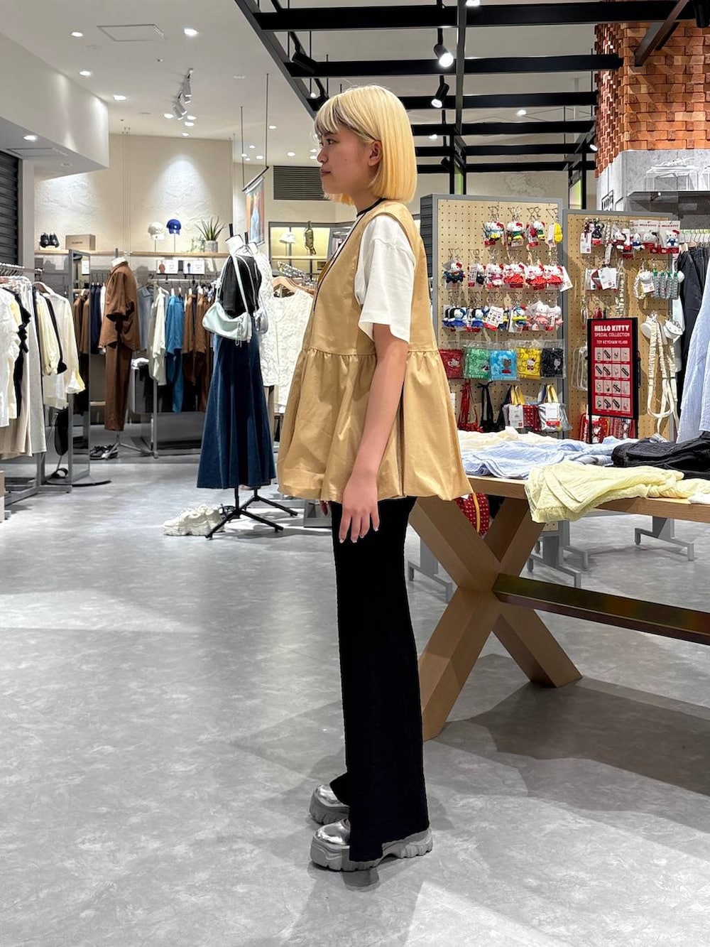 グレー系のスニーカー、ホワイト系のTシャツ/カットソー、ベージュ系のベストを着用したレディースの春コーディネートの2枚目の写真