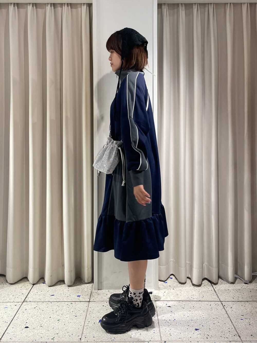 シルバー系のショルダーバッグ、ブラック系のスニーカー、ブルー系のワンピースを着用したレディースの夏コーディネートの3枚目の写真