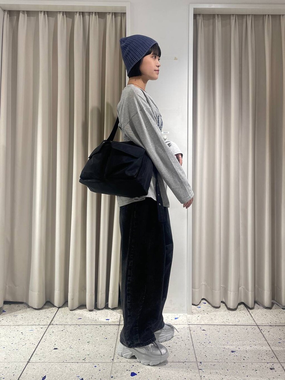 ブラック系のデニムパンツ、ブラック系のショルダーバッグ、シルバー系のスニーカーを着用したレディースの秋コーディネートの2枚目の写真