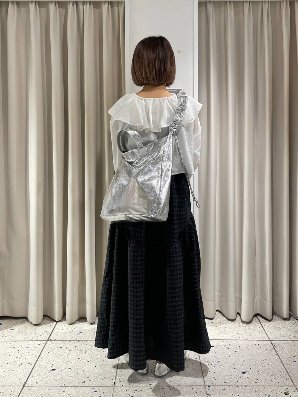 グレー系のトートバッグ、ホワイト系のシャツ/ブラウス、ブラック系のワンピースを着用したレディースの春コーディネートの3枚目の写真