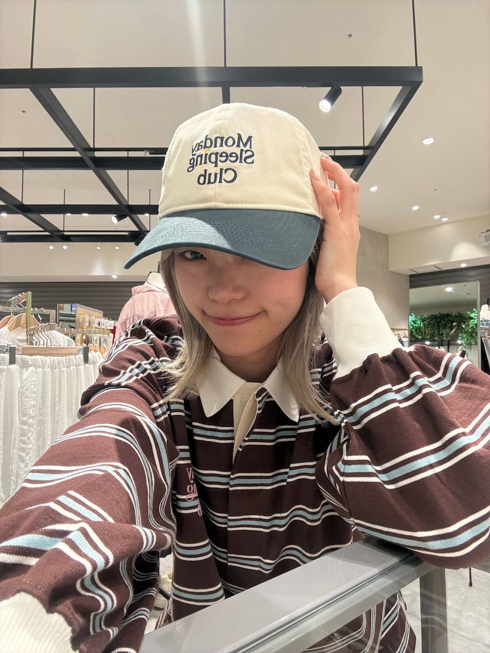 ブラウン系のTシャツ/カットソー、ホワイト系のキャップ、ブルー系のシュシュを着用したレディースの春コーディネートの2枚目の写真