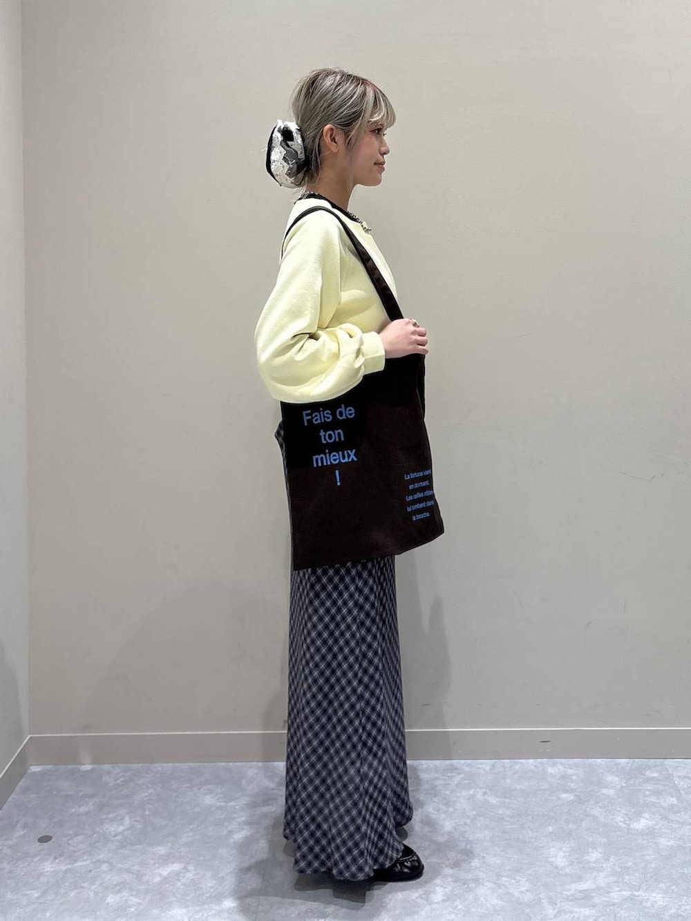 ブラウン系のトートバッグ、ブラック系のローファー、イエロー系のスウェットを着用したレディースの冬コーディネートの4枚目の写真