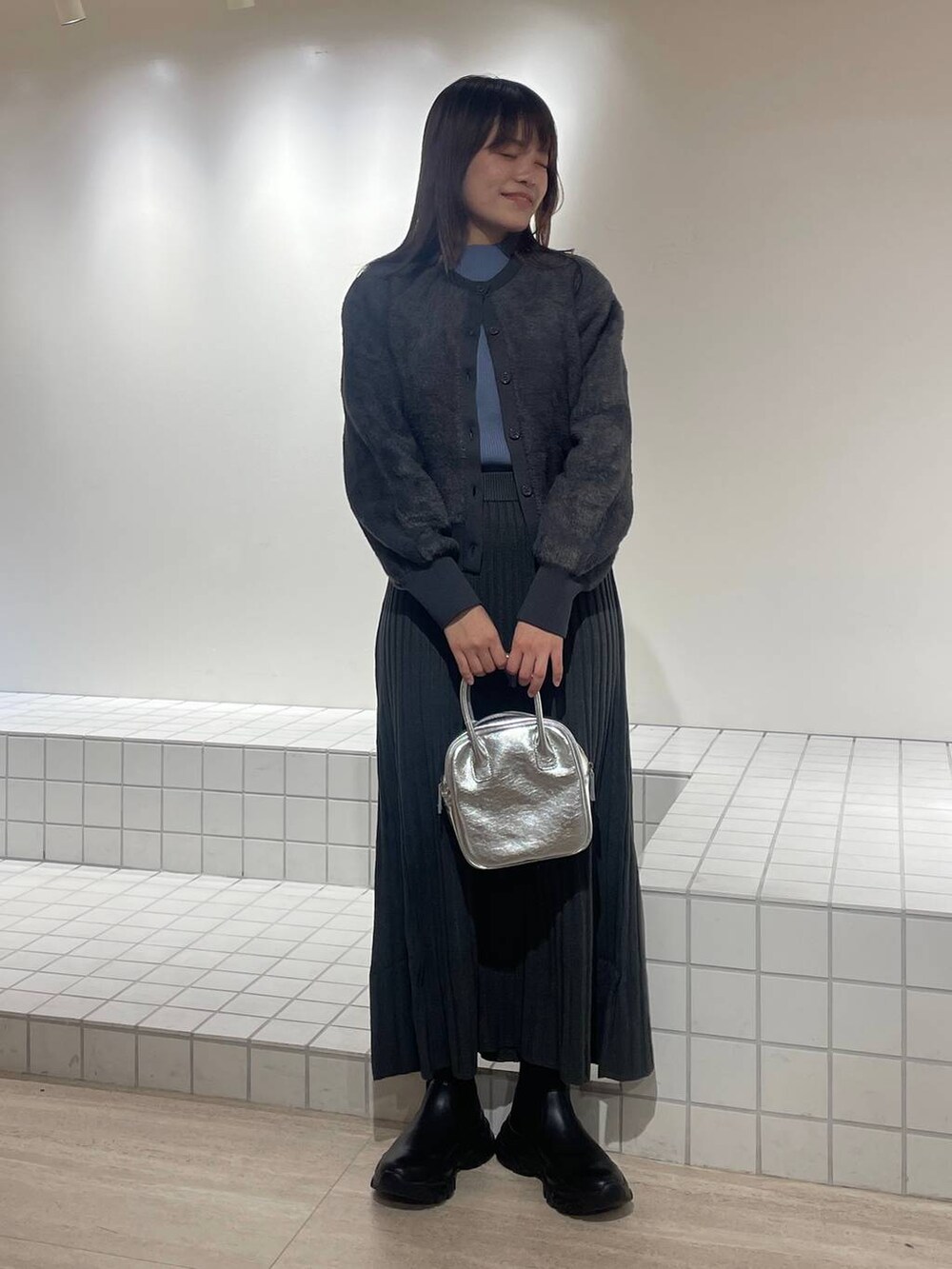 ブルー系のニット/セーター、グレー系のワンピース、シルバー系のボストンバッグを着用したレディースの冬コーディネートの2枚目の写真
