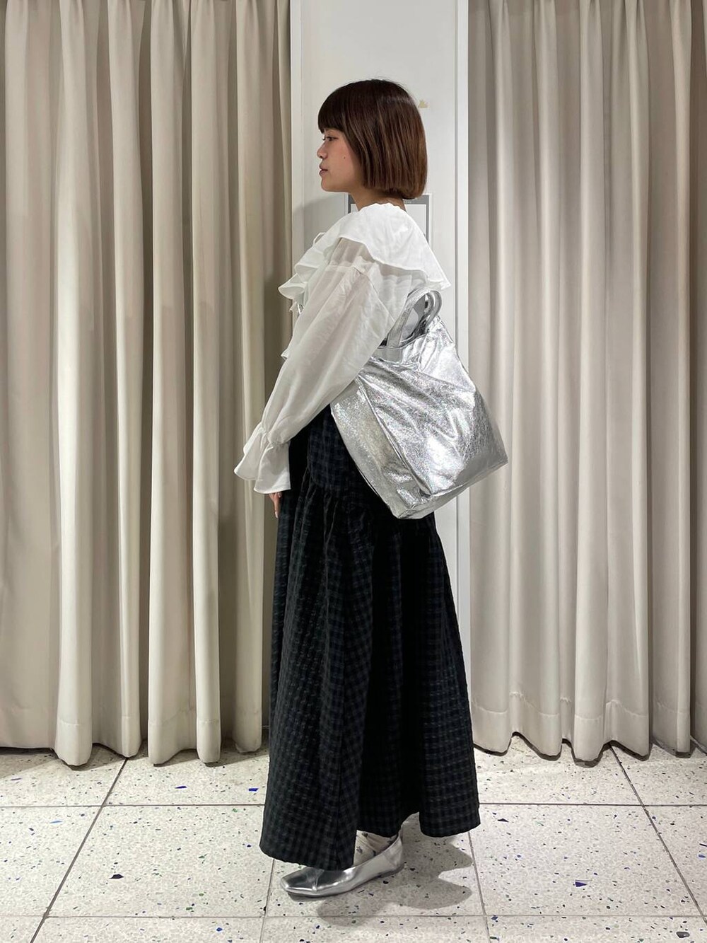 グレー系のトートバッグ、ホワイト系のシャツ/ブラウス、ブラック系のワンピースを着用したレディースの春コーディネートの2枚目の写真