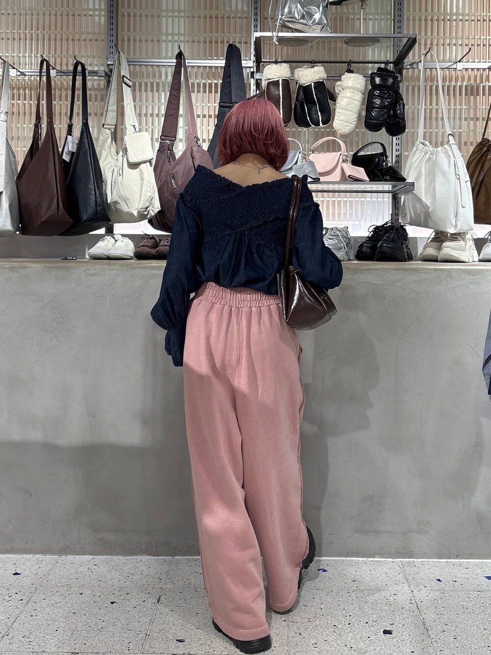 ブラック系のブーツ、ブラウン系のショルダーバッグ、ピンク系のスウェットパンツを着用したレディースの冬コーディネートの3枚目の写真