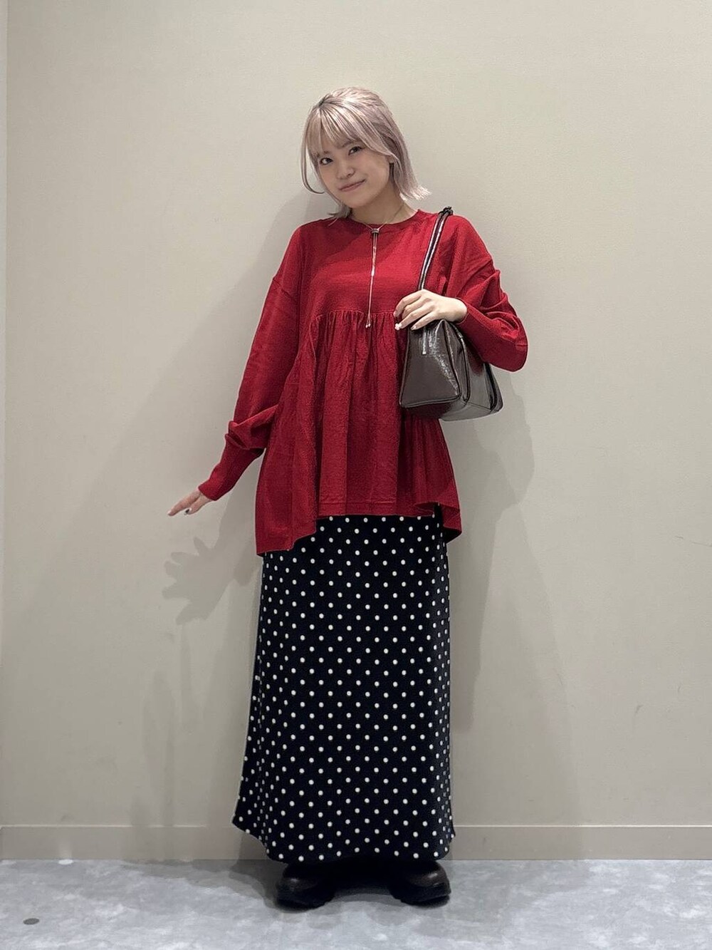 ブラック系のスカート、レッド系のニット/セーター、レッド系のボストンバッグを着用したレディースの秋コーディネートの6枚目の写真