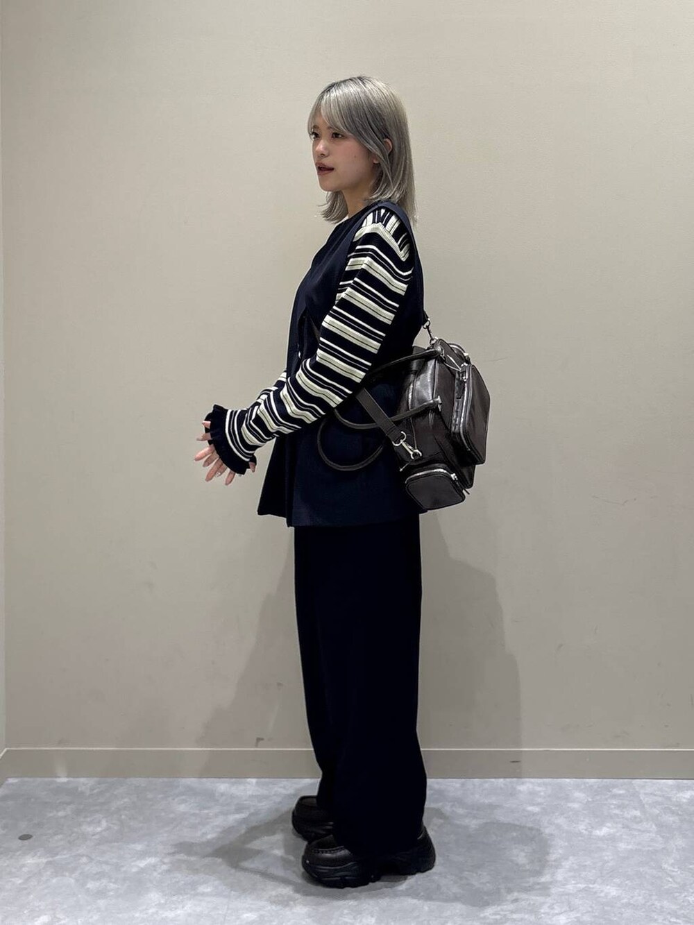 ブルー系のスラックス、ブルー系のベスト、ブラウン系のボストンバッグを着用したレディースの冬コーディネートの2枚目の写真