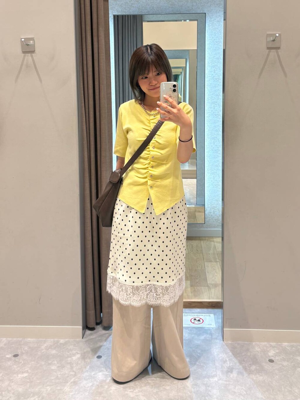 ベージュ系のデニムパンツ、ブラウン系のショルダーバッグ、ホワイト系のスカートを着用したレディースの夏コーディネートの2枚目の写真