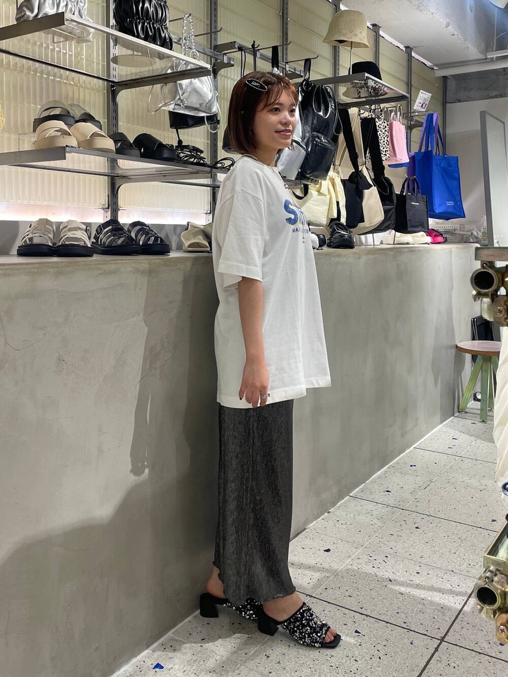 ホワイト系のTシャツ/カットソー、ブラック系のスカート、シルバー系のサンダルを着用したレディースの夏コーディネートの2枚目の写真