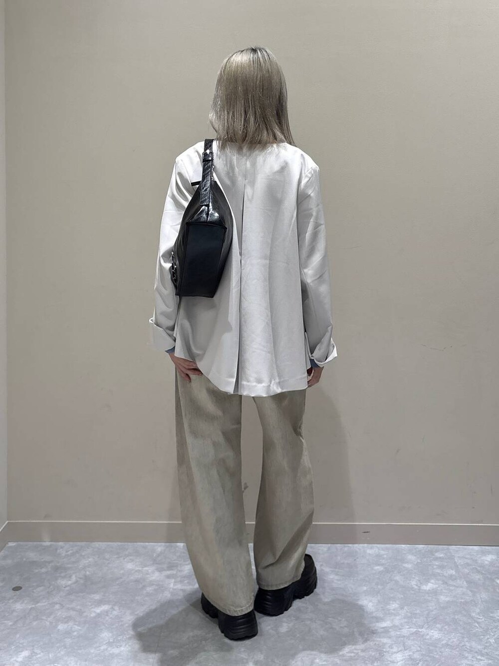 ベージュ系のデニムパンツ、ホワイト系のテーラードジャケット、ブラック系のショルダーバッグを着用したレディースの冬コーディネートの3枚目の写真