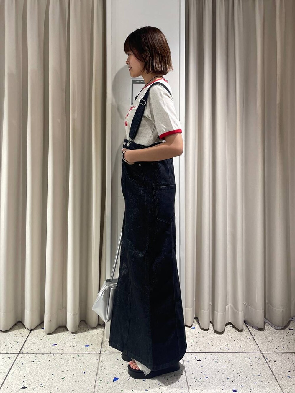 ホワイト系のサンダル、ホワイト系のTシャツ/カットソー、ブラック系のジャンパースカートを着用したレディースの夏コーディネートの4枚目の写真