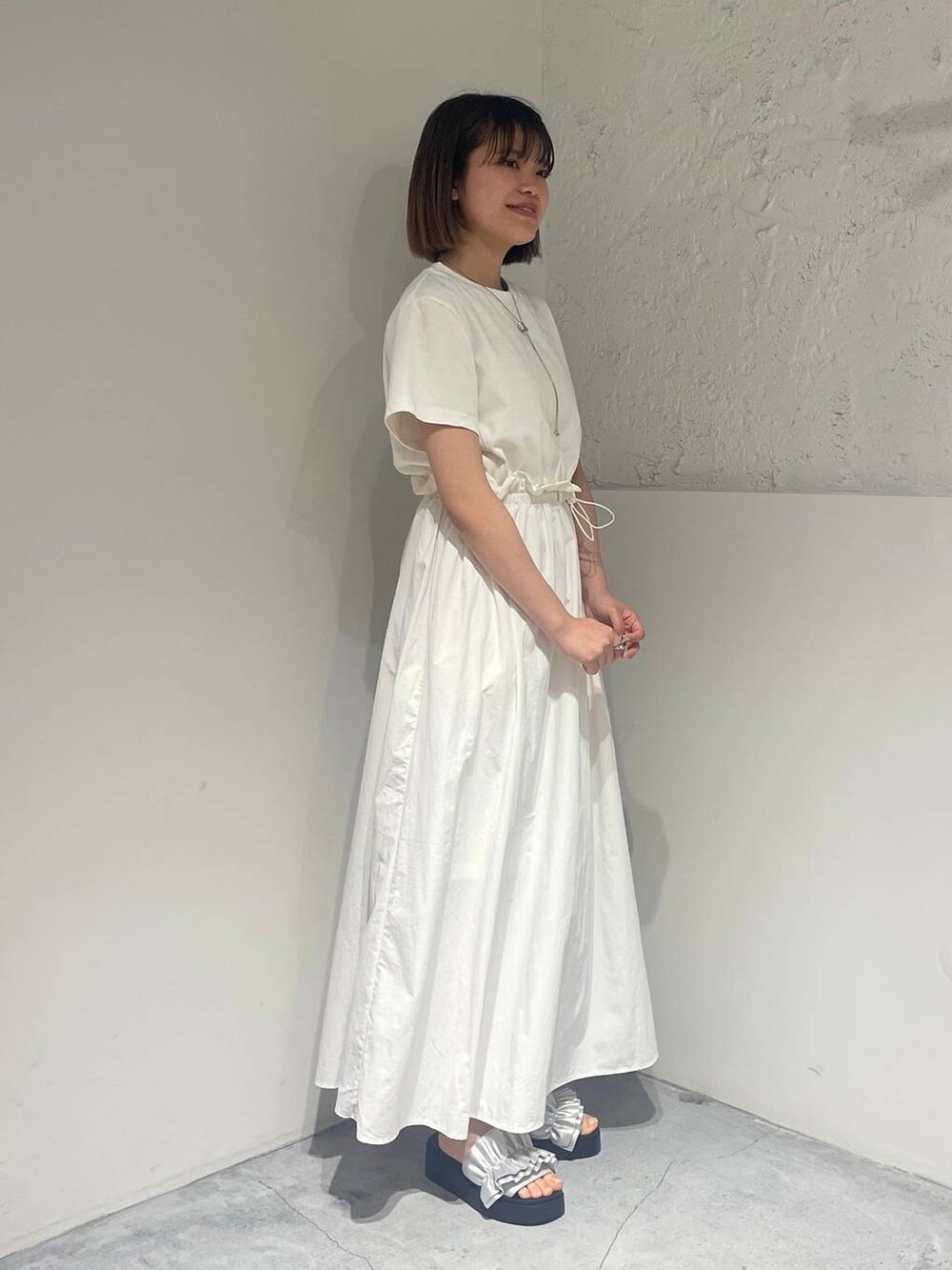 シルバー系のサンダル、ホワイト系のワンピース、シルバー系のネックレスを着用したレディースの春コーディネートの4枚目の写真