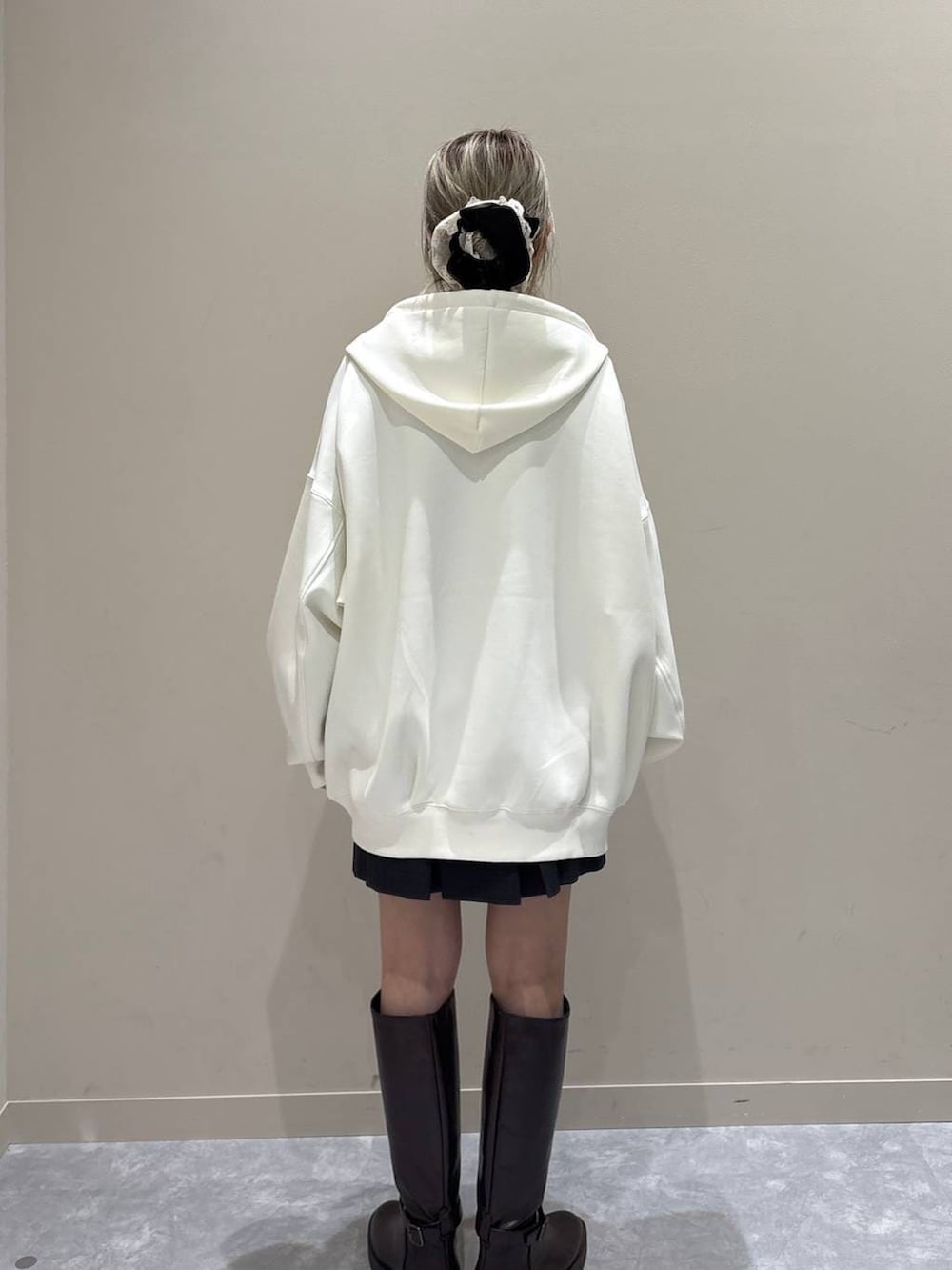 ベージュ系のパーカー、ブラウン系のブーツ、グレー系のスカートを着用したレディースの春コーディネートの3枚目の写真