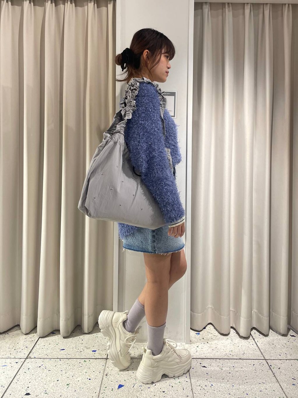 ホワイト系のカーディガン/ボレロ、グレー系のトートバッグ、ブルー系のスカートを着用したレディースの冬コーディネートの2枚目の写真