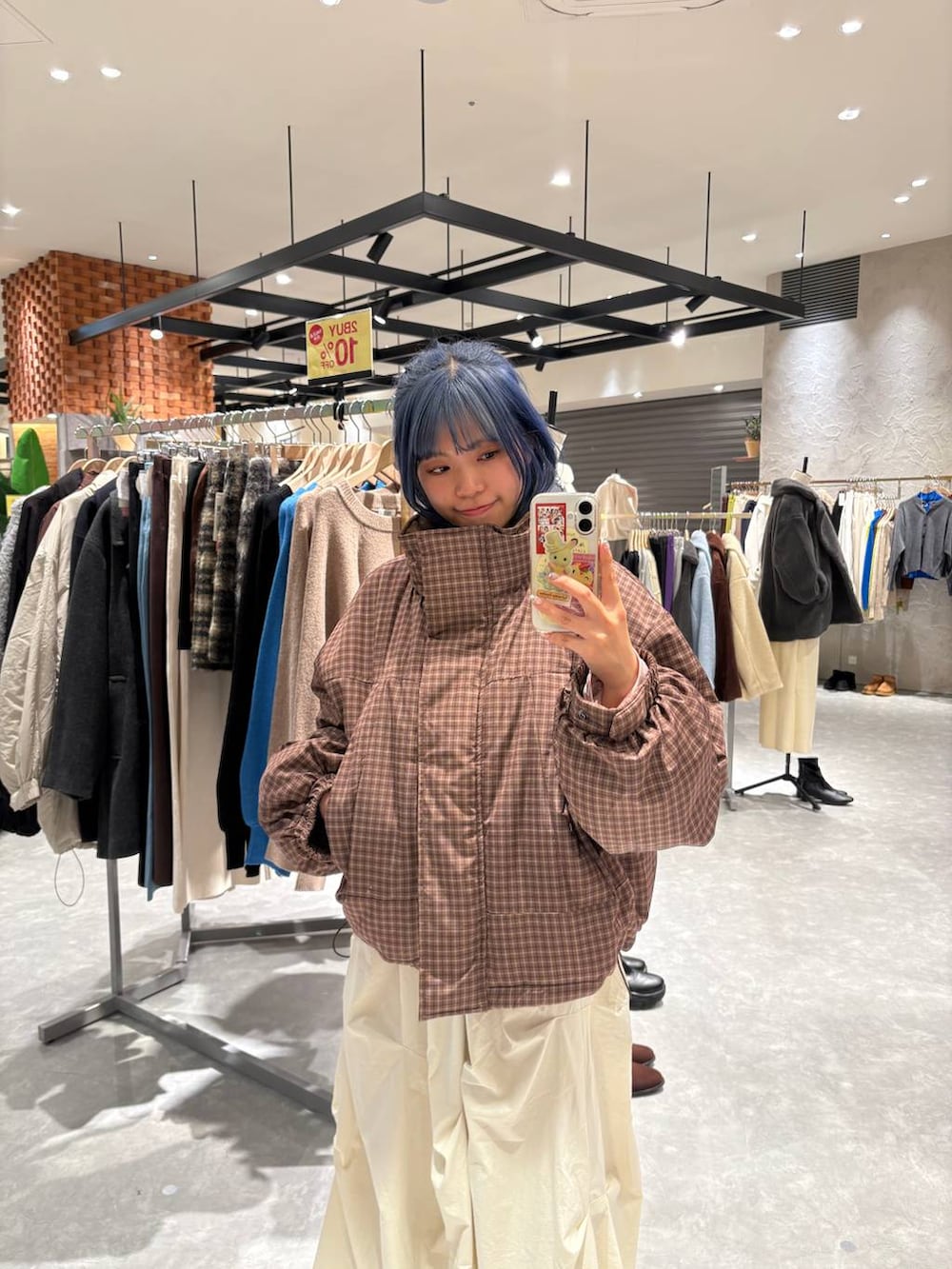 ブラック系のブーツ、ブラウン系のブルゾン、ホワイト系のスカートを着用したレディースの冬コーディネートの5枚目の写真