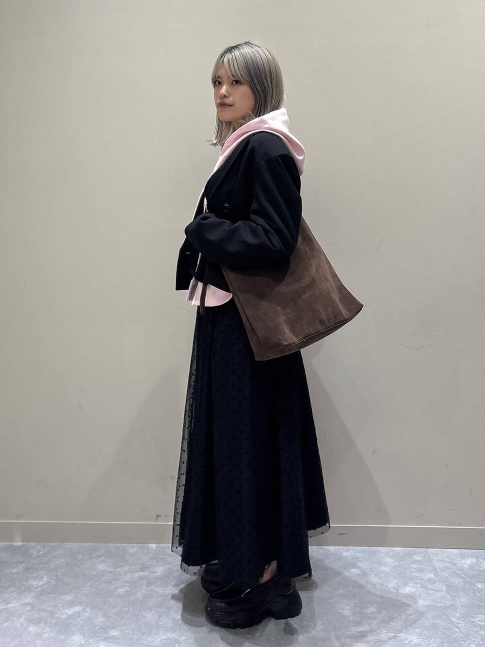 ブラウン系のショルダーバッグ、ブラック系のテーラードジャケット、ブラック系のスカートを着用したレディースの冬コーディネートの4枚目の写真