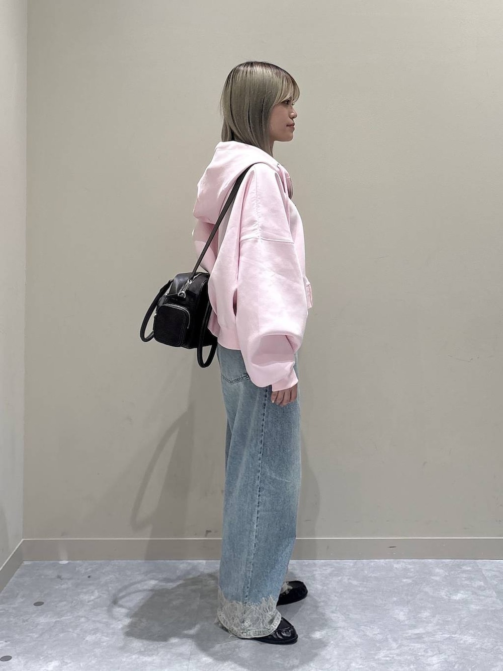 ピンク系のパーカー、ブルー系のデニムパンツ、ブラウン系のローファーを着用したレディースの春コーディネートの2枚目の写真