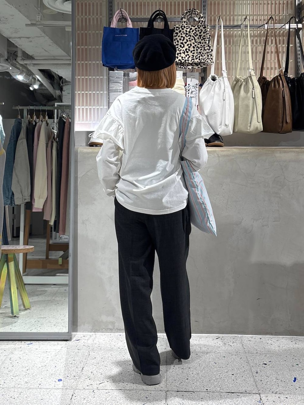 グレー系のスラックス、その他のトートバッグ、ホワイト系のTシャツ/カットソーを着用したレディースの春コーディネートの3枚目の写真