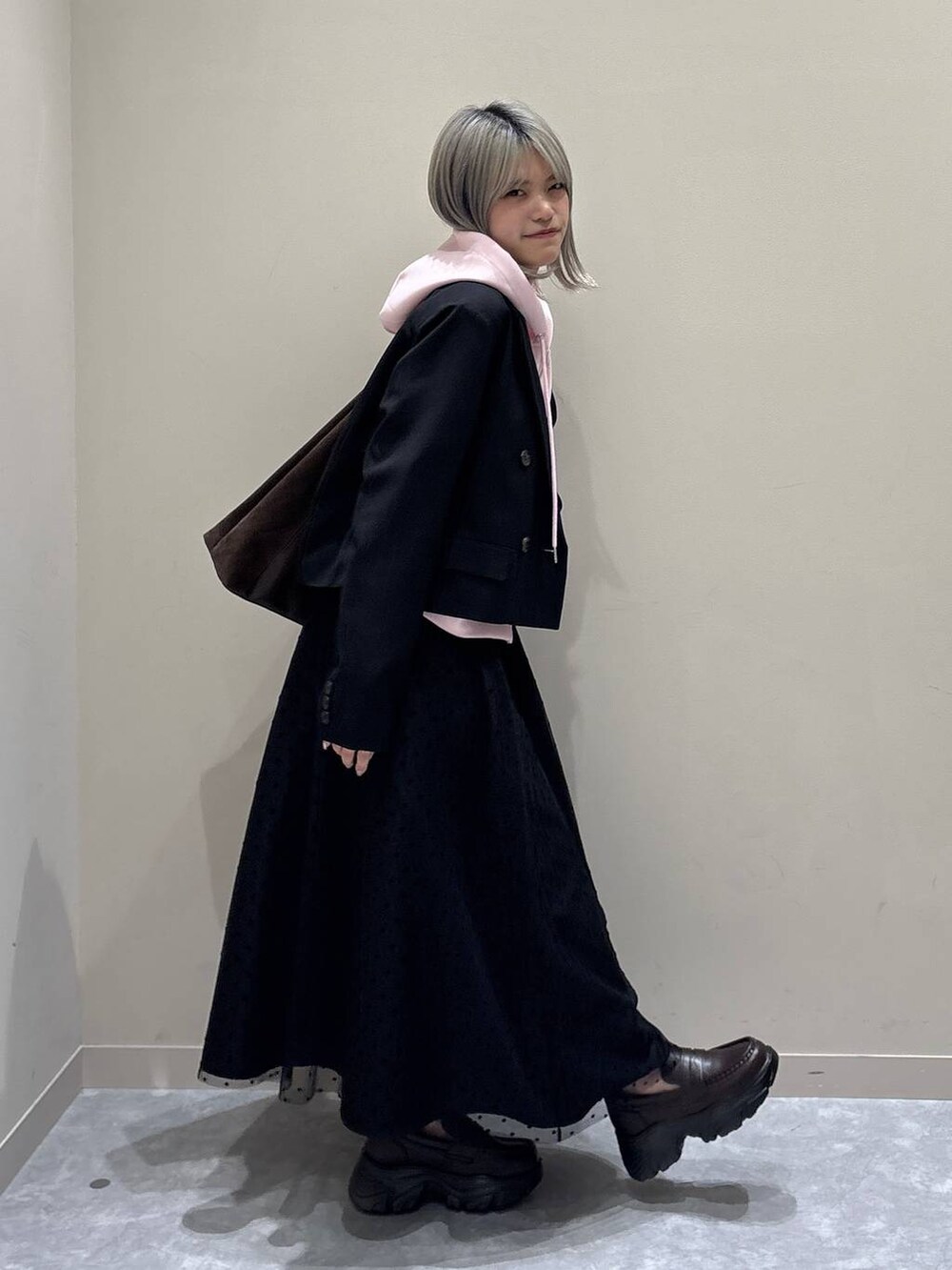 ブラウン系のショルダーバッグ、ブラック系のテーラードジャケット、ブラック系のスカートを着用したレディースの冬コーディネートの5枚目の写真