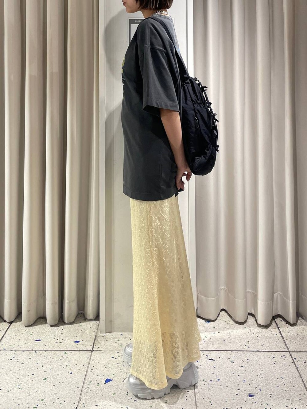 イエロー系のスカート、シルバー系のスニーカー、ブラック系のバックパック/リュックを着用したレディースの夏コーディネートの2枚目の写真