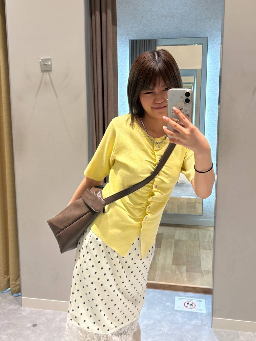 ベージュ系のデニムパンツ、ブラウン系のショルダーバッグ、ホワイト系のスカートを着用したレディースの夏コーディネートの3枚目の写真