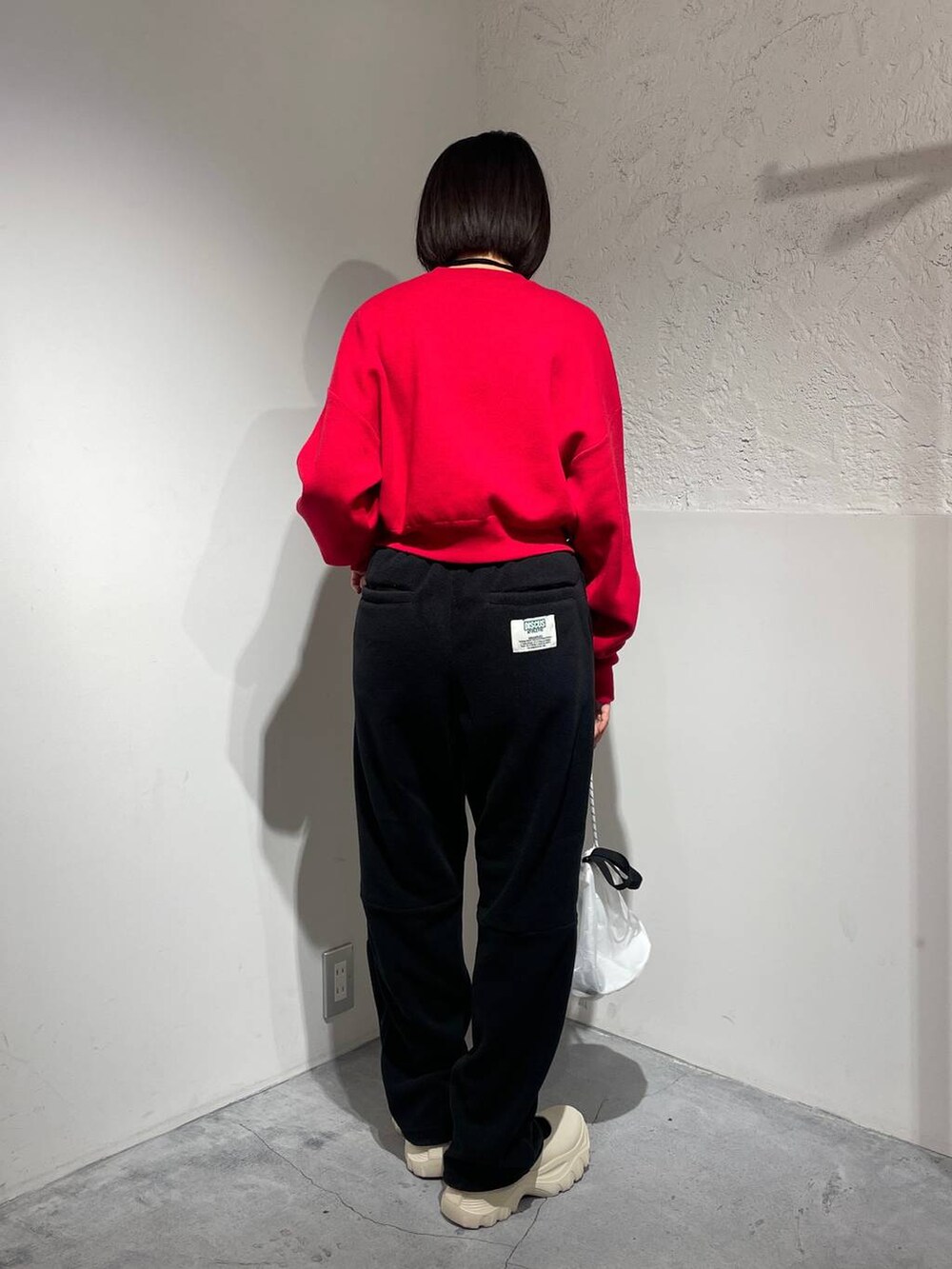 ブラック系のその他パンツ、ホワイト系のスニーカー、レッド系のニット/セーターを着用したレディースの秋コーディネートの3枚目の写真