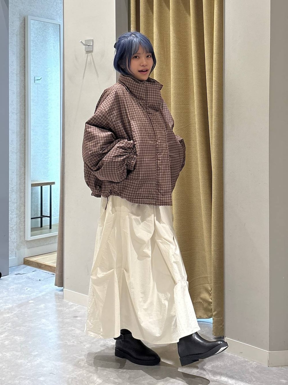 ブラック系のブーツ、ブラウン系のブルゾン、ホワイト系のスカートを着用したレディースの冬コーディネートの4枚目の写真