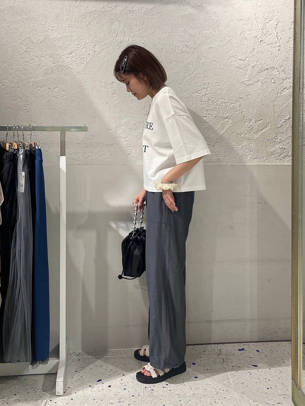 グレー系のセットアップ、ホワイト系のスニーカー、ブラック系のショルダーバッグを着用したレディースの夏コーディネートの2枚目の写真