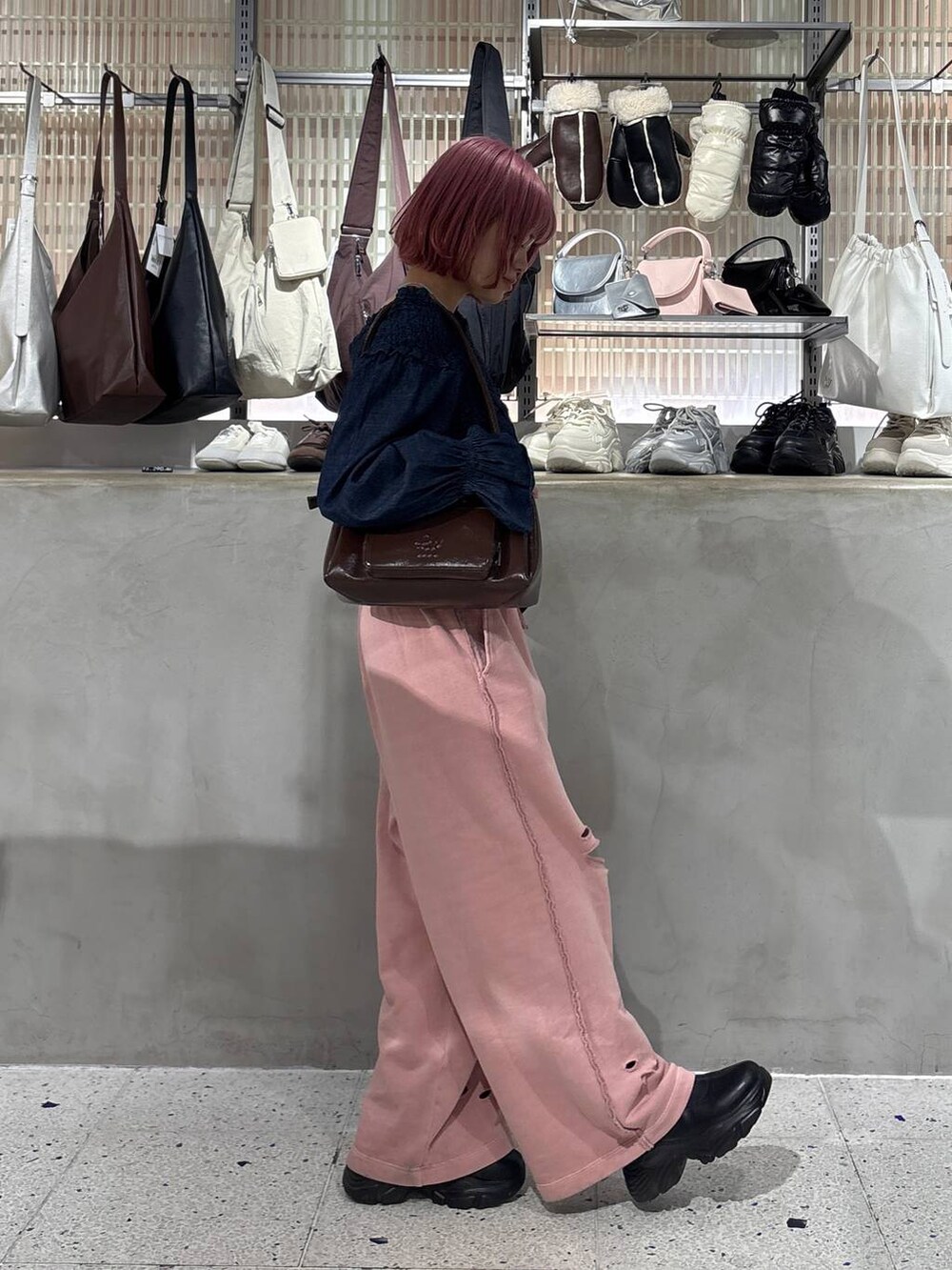 ブラック系のブーツ、ブラウン系のショルダーバッグ、ピンク系のスウェットパンツを着用したレディースの冬コーディネートの4枚目の写真