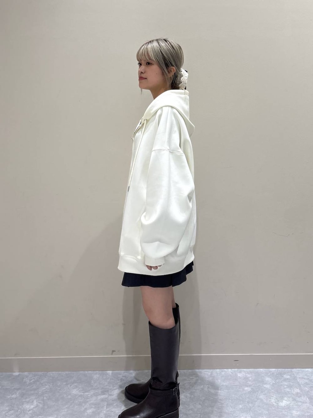 ベージュ系のパーカー、ブラウン系のブーツ、グレー系のスカートを着用したレディースの春コーディネートの2枚目の写真