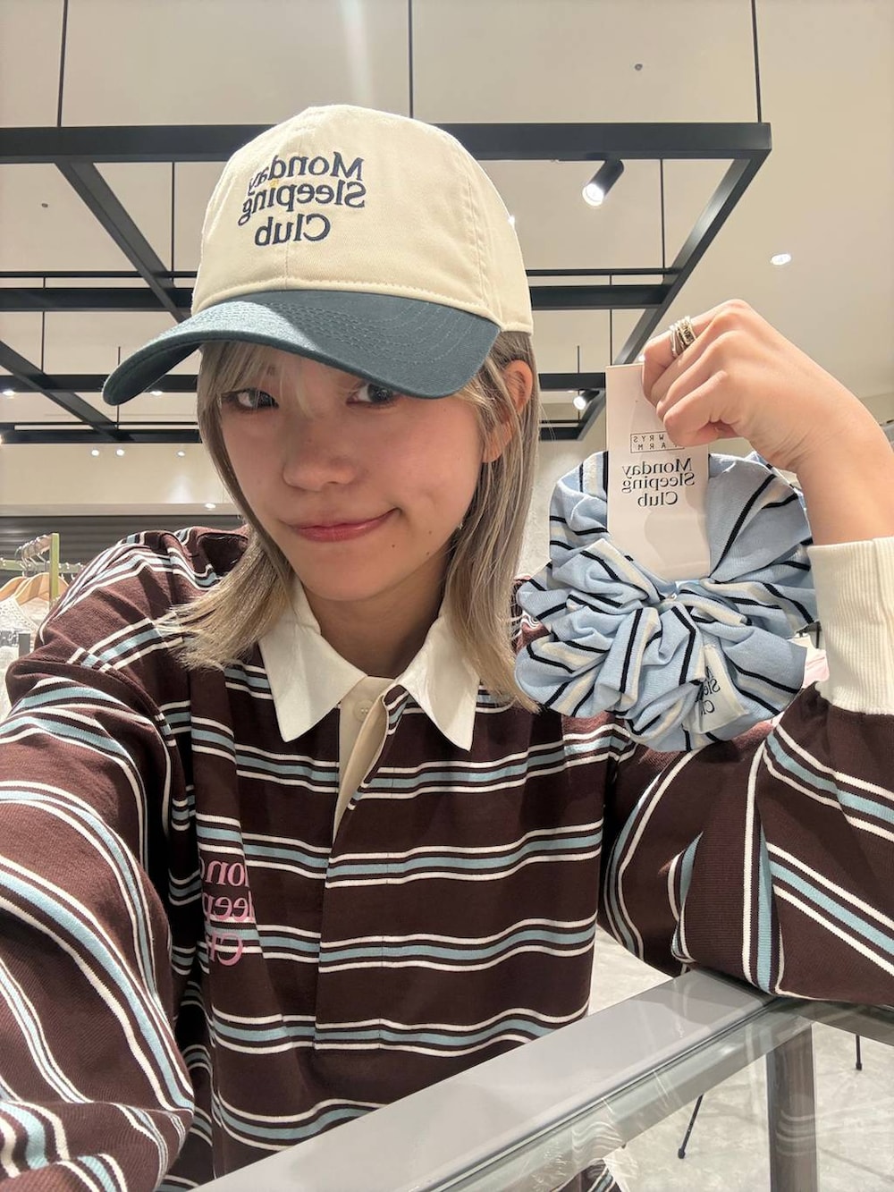 ブラウン系のTシャツ/カットソー、ホワイト系のキャップ、ブルー系のシュシュを着用したレディースの春コーディネートの3枚目の写真