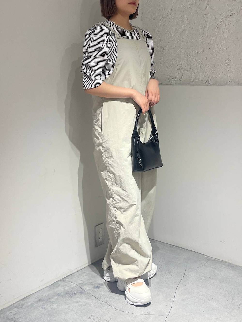 ホワイト系のサンダル、ブラック系のハンドバッグ、ホワイト系のサロペット/オーバーオールを着用したレディースの春コーディネートの2枚目の写真