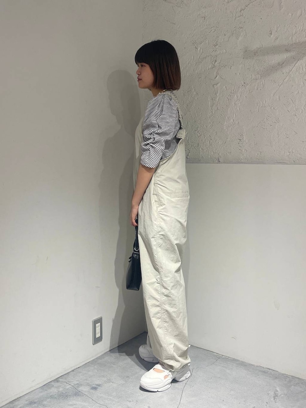 ホワイト系のサンダル、ブラック系のハンドバッグ、ホワイト系のサロペット/オーバーオールを着用したレディースの春コーディネートの3枚目の写真