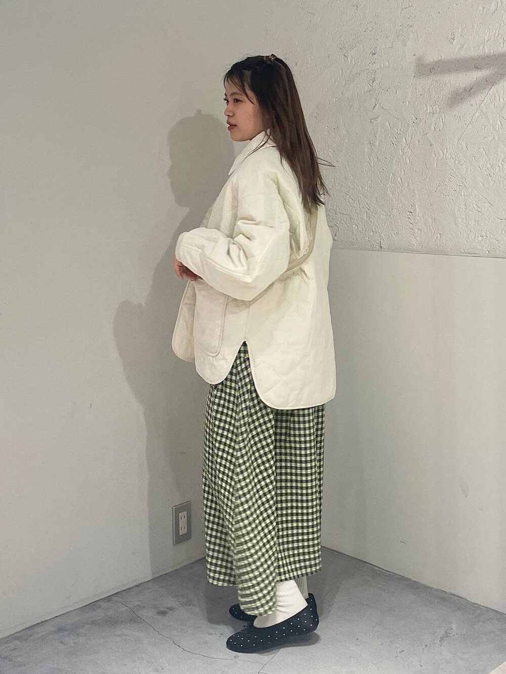 グリーン系のワンピース、ホワイト系のミリタリージャケット、ブラック系のバレエシューズを着用したレディースの冬コーディネートの2枚目の写真