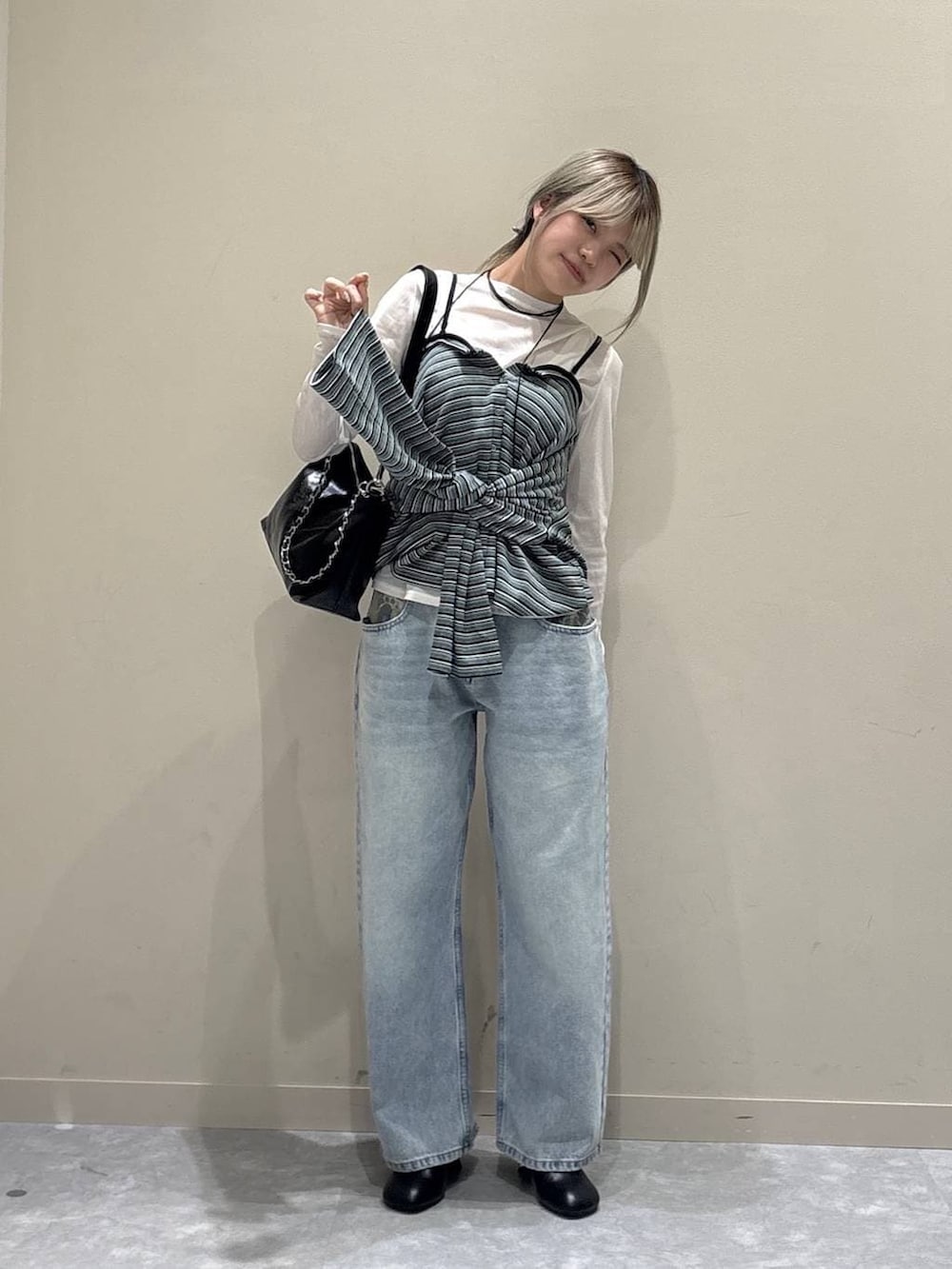 ブルー系のデニムパンツ、ホワイト系のTシャツ/カットソー、ブラック系のショルダーバッグを着用したレディースの春コーディネートの5枚目の写真