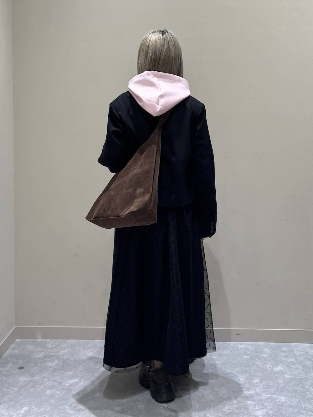 ブラウン系のショルダーバッグ、ブラック系のテーラードジャケット、ブラック系のスカートを着用したレディースの冬コーディネートの3枚目の写真