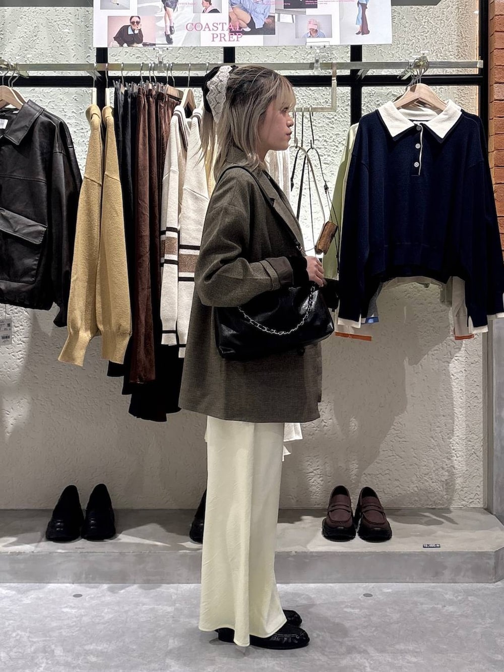 イエロー系のスカート、ブラウン系のテーラードジャケット、ブラック系のローファーを着用したレディースの春コーディネートの4枚目の写真