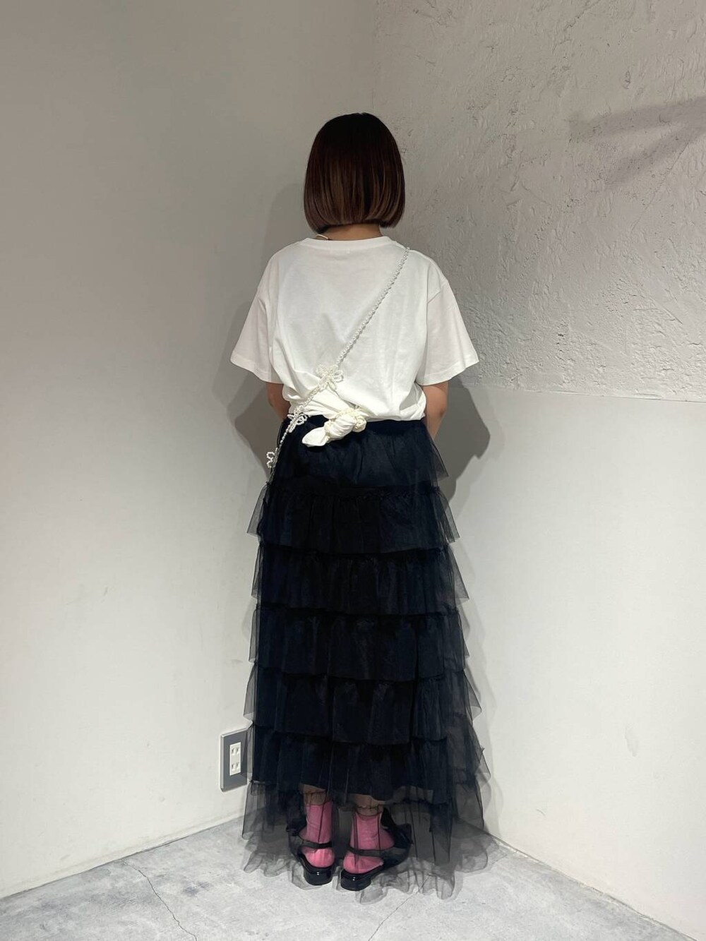 ブラック系のパンプス、ブラック系のスカート、ホワイト系のTシャツ/カットソーを着用したレディースの夏コーディネートの3枚目の写真