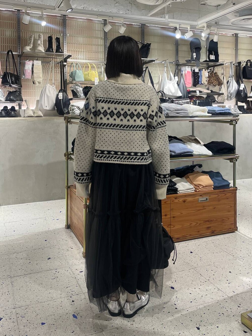ブラック系のスカート、シルバー系のローファー、ブラック系のショルダーバッグを着用したレディースの秋コーディネートの3枚目の写真