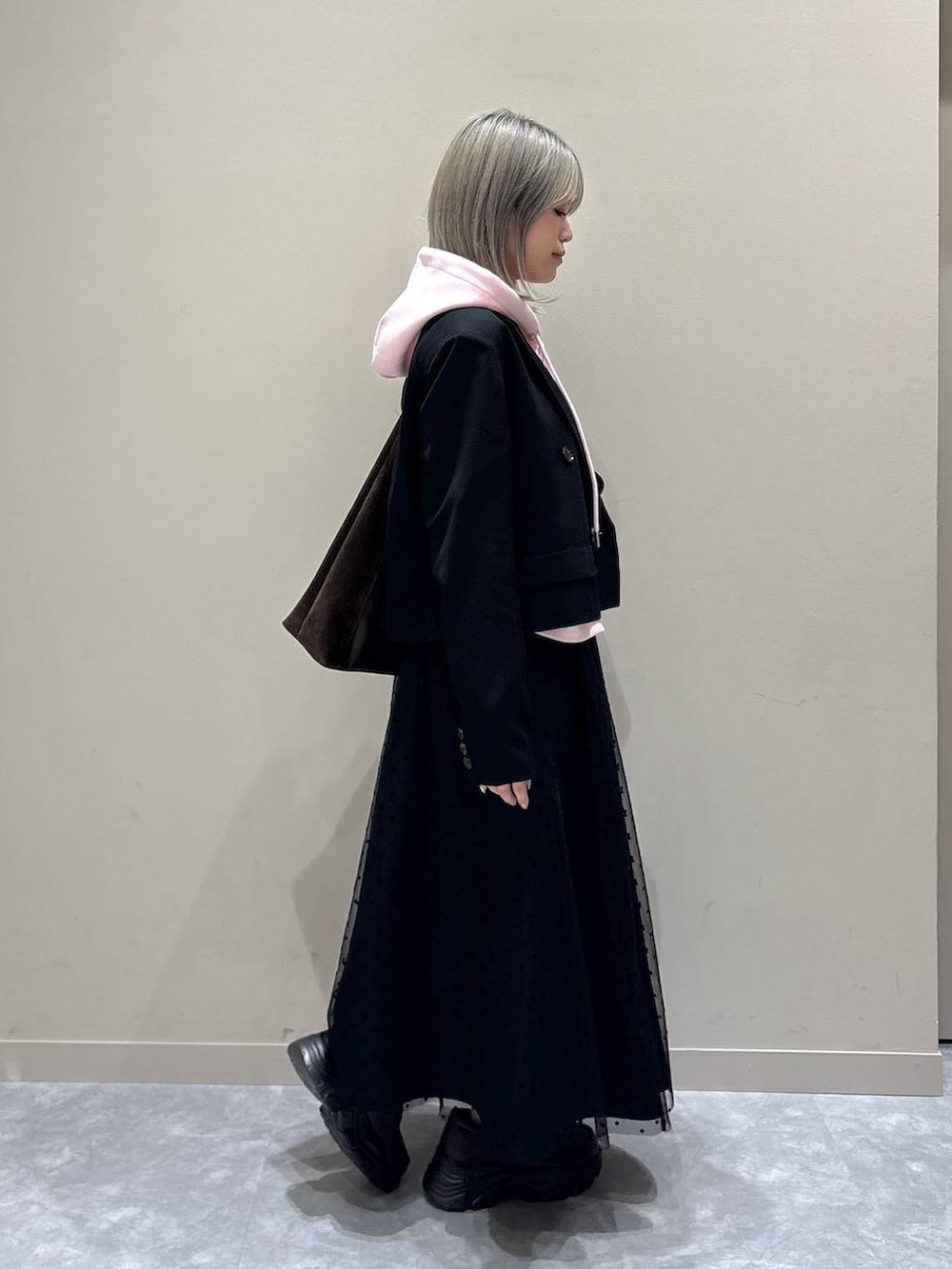 ブラウン系のショルダーバッグ、ブラック系のテーラードジャケット、ブラック系のスカートを着用したレディースの冬コーディネートの2枚目の写真