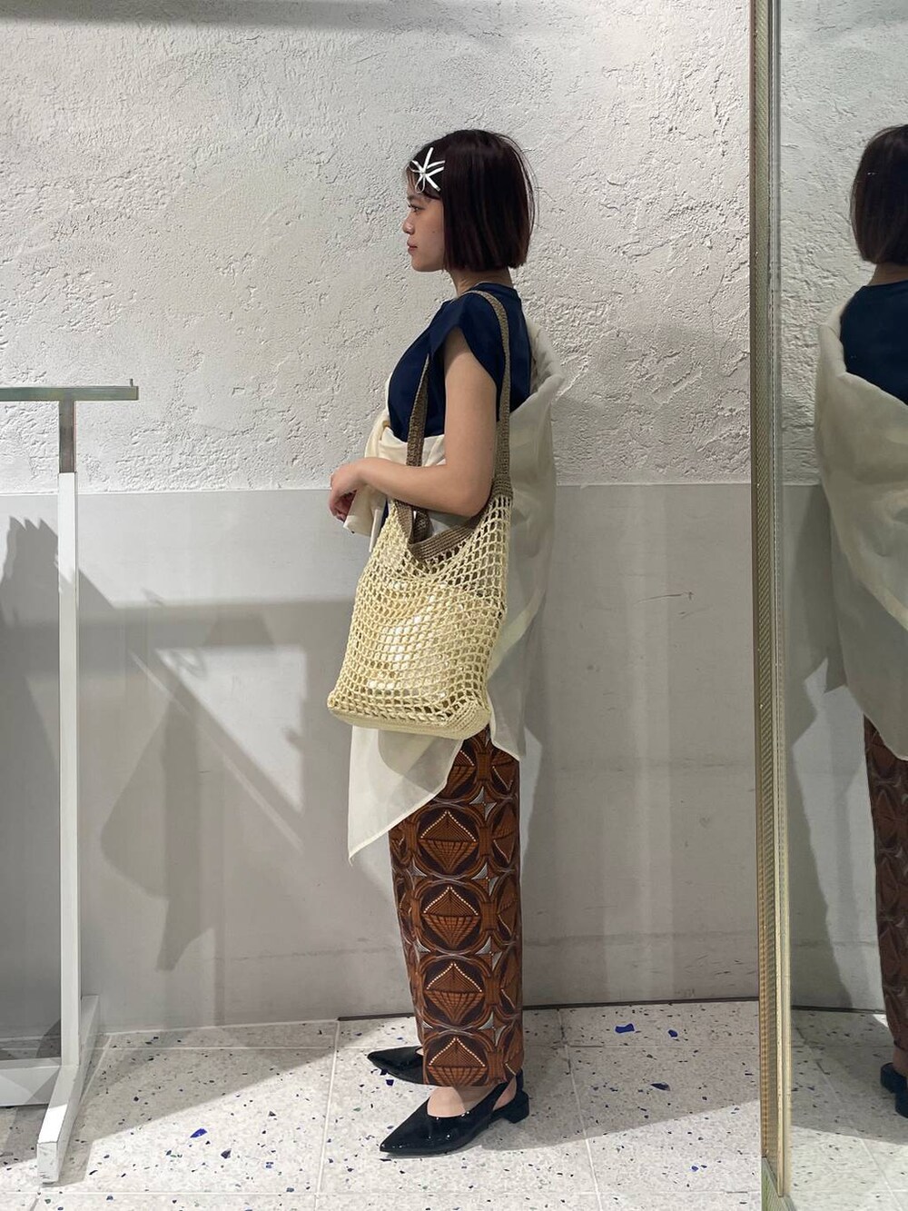 ベージュ系のショルダーバッグ、ブラウン系のスカート、ホワイト系のシャツ/ブラウスを着用したレディースの春コーディネートの3枚目の写真