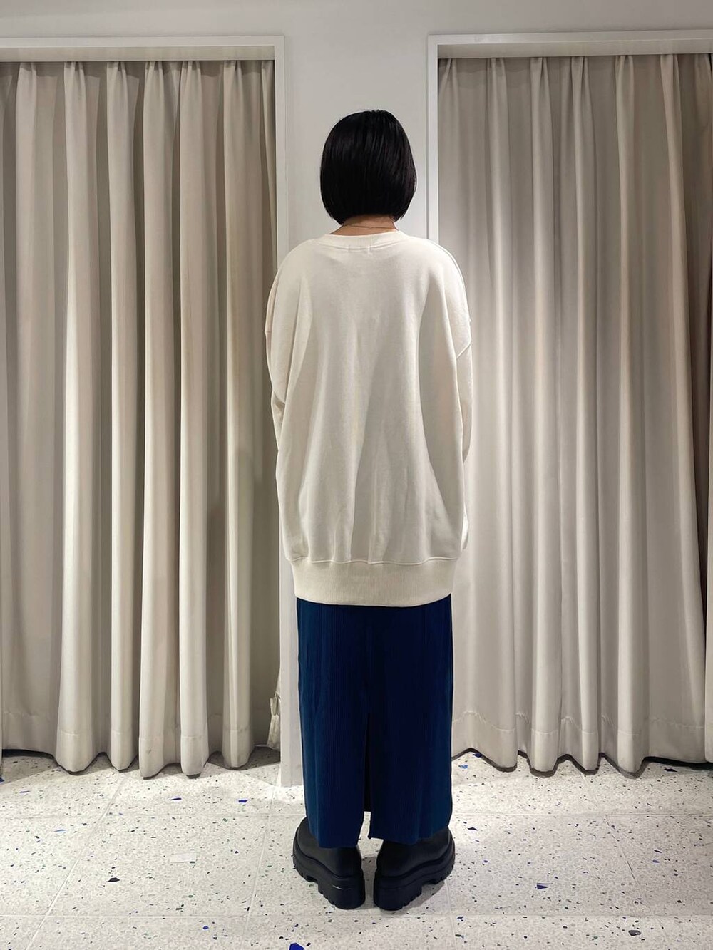 ブルー系のスカート、ホワイト系のハンドバッグ、ブラック系のブーツを着用したレディースの秋コーディネートの3枚目の写真