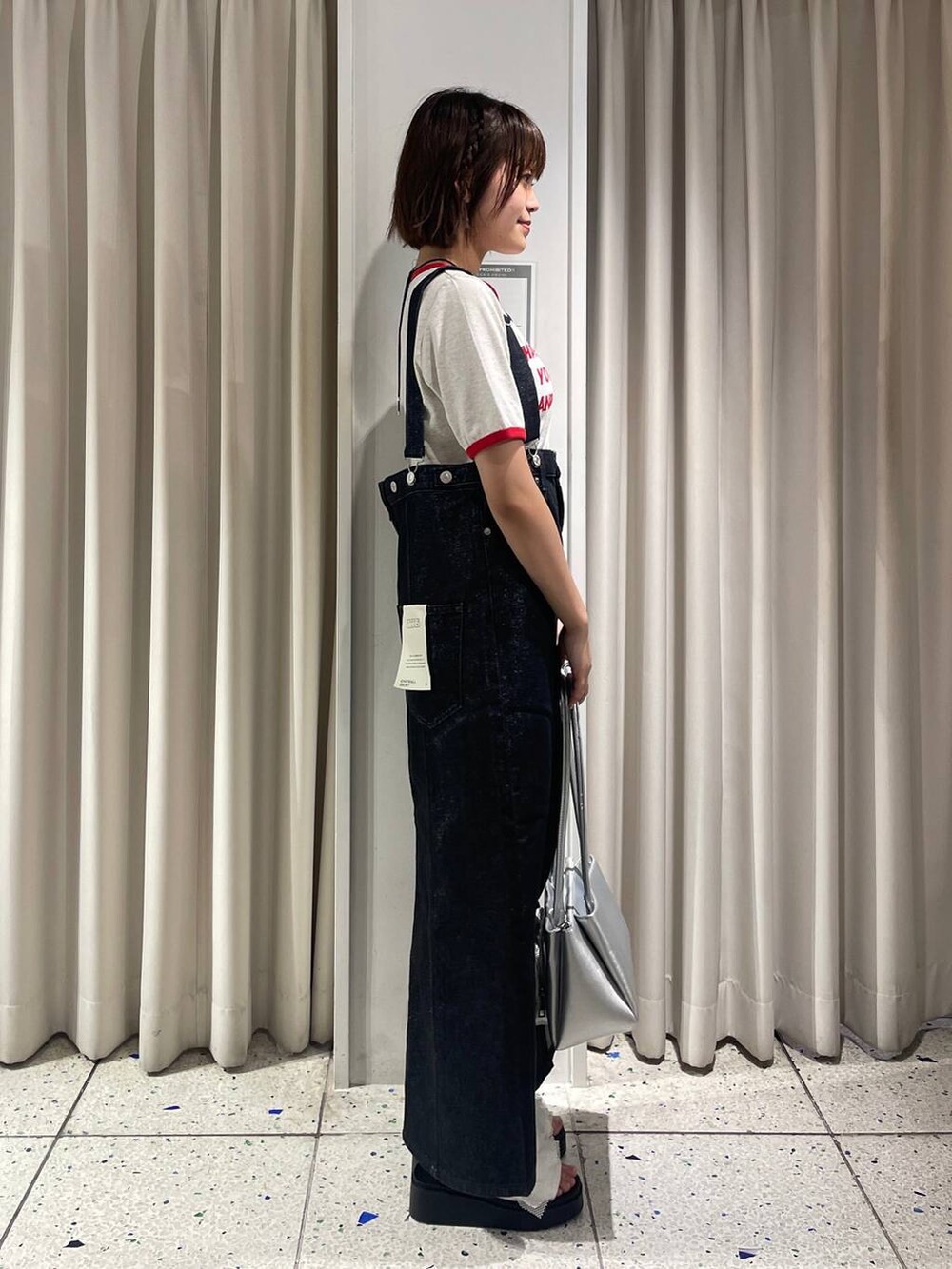 ホワイト系のサンダル、ホワイト系のTシャツ/カットソー、ブラック系のジャンパースカートを着用したレディースの夏コーディネートの2枚目の写真