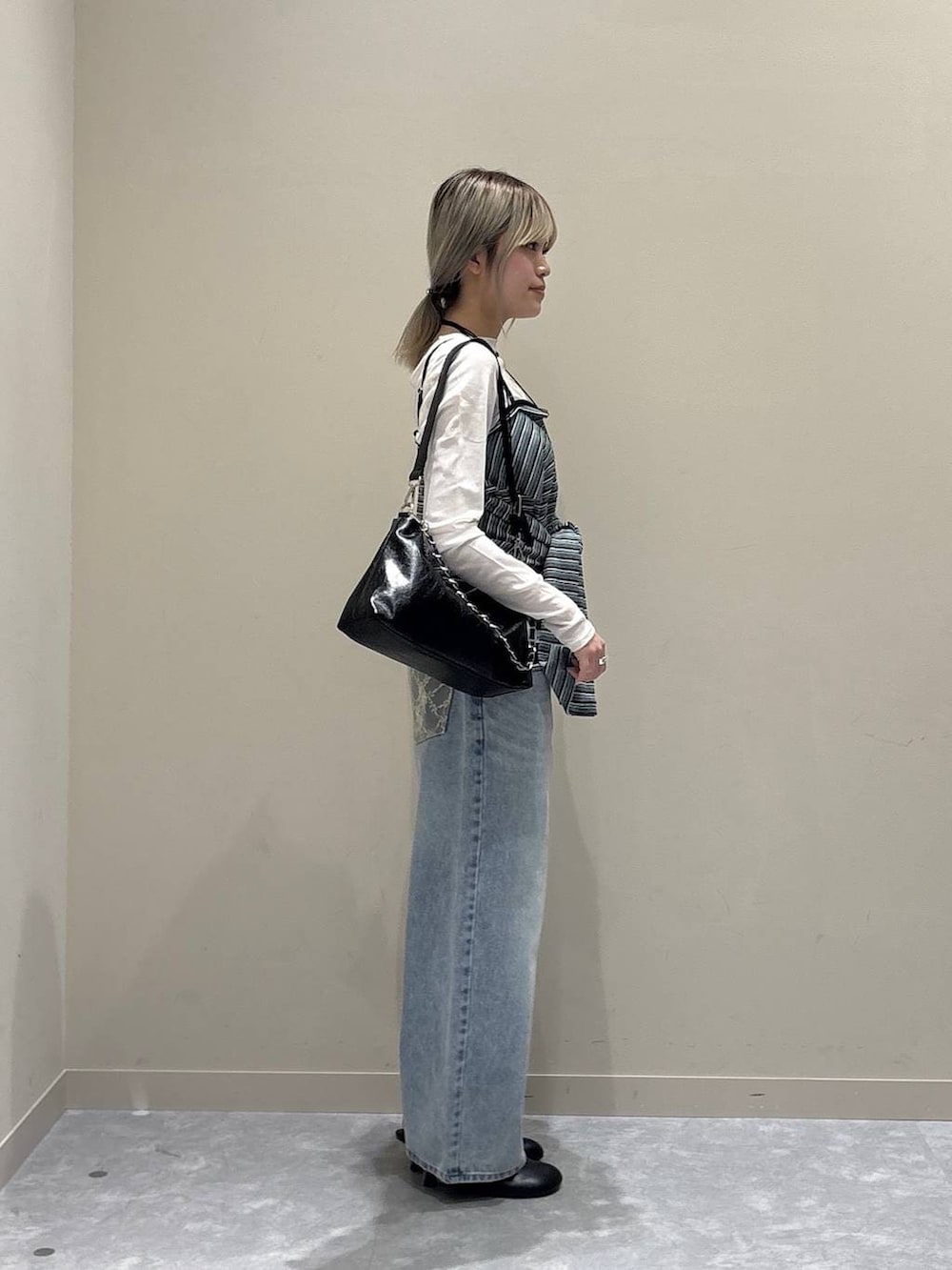 ブルー系のデニムパンツ、ホワイト系のTシャツ/カットソー、ブラック系のショルダーバッグを着用したレディースの春コーディネートの4枚目の写真