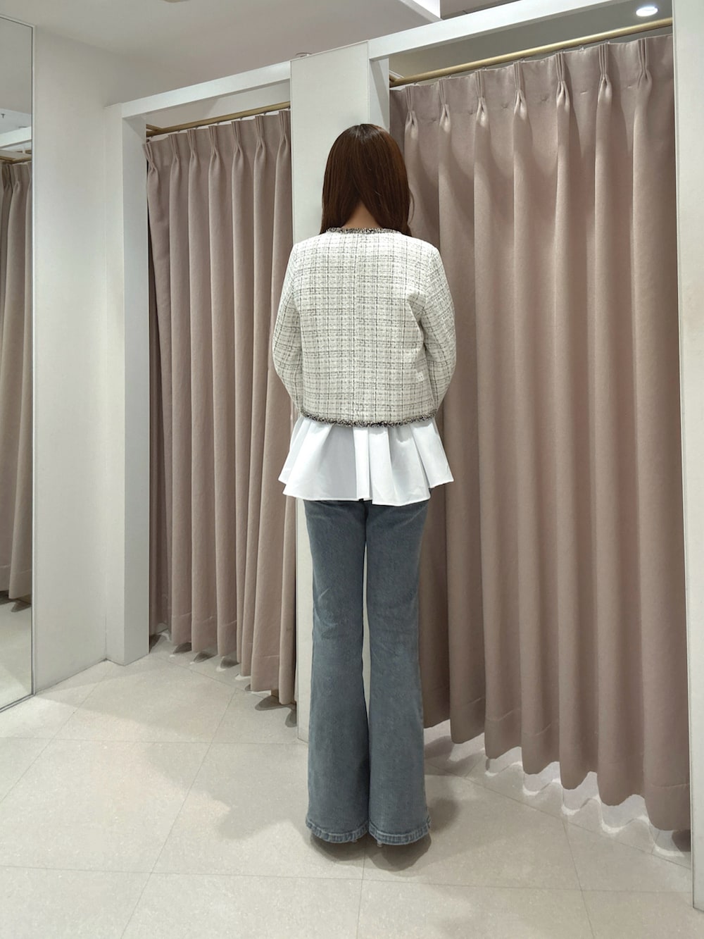 ホワイト系のノーカラージャケット、ホワイト系のニット/セーター、ブルー系のデニムパンツを着用したレディースの秋コーディネートの4枚目の写真