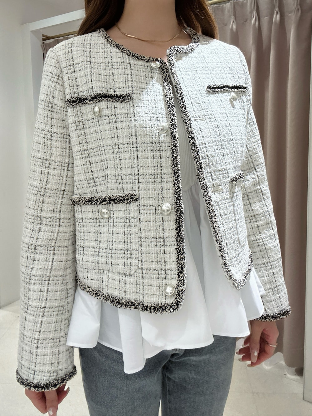 ホワイト系のノーカラージャケット、ホワイト系のニット/セーター、ブルー系のデニムパンツを着用したレディースの秋コーディネートの5枚目の写真