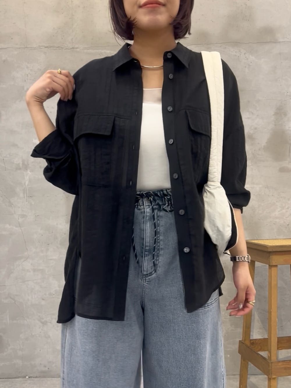 ブルー系のデニムパンツ、ブラック系のシャツ/ブラウス、ブラック系のショルダーバッグを着用したレディースの夏コーディネートの5枚目の写真